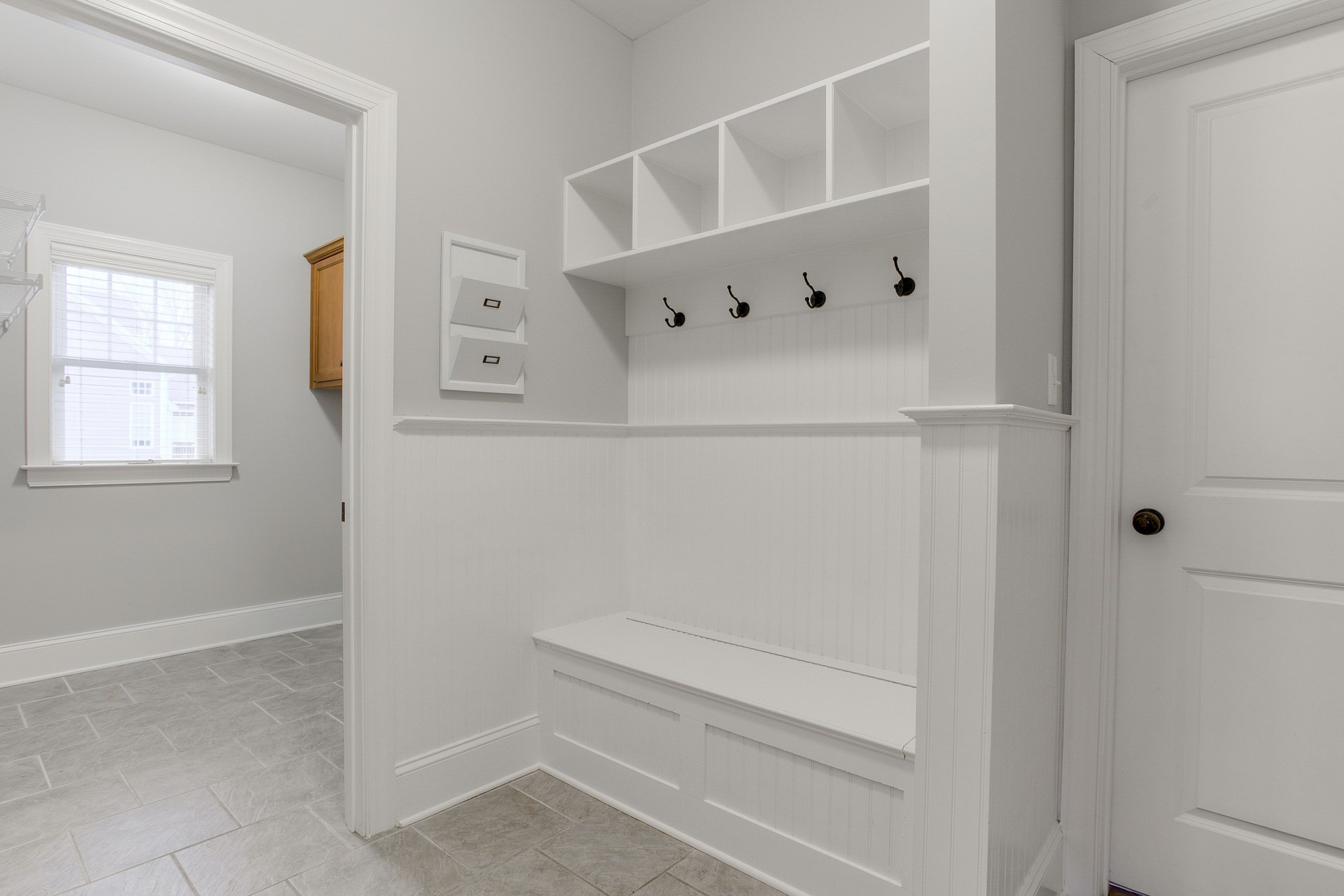 Spacious Mudroom With Bench, Hooks, Storage, And Adjacent Laundry Space